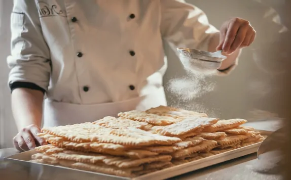 Il pasticcere dispone le chiacchiere sul vassoio