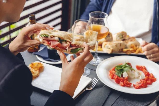 Panino con prosciutto crudo, stracciatella e insalata tenuto in mano